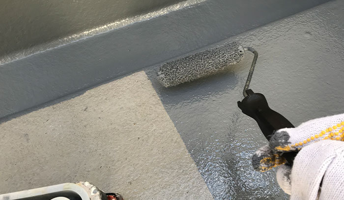 ベランダの床に防水工事を行い、防水機能を回復させている様子