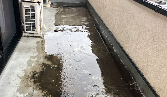 ベランダが排水不良によって水たまりができている