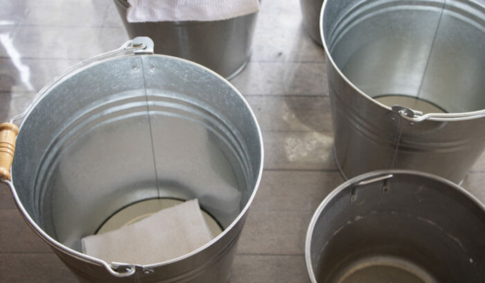 雨漏りが起きて床にバケツを置いている風景