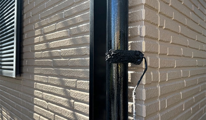 付帯部（雨どい）に塗装をしている様子