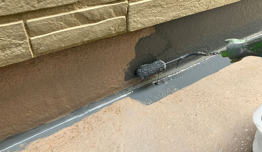 ベランダの床面にトップコートを塗布している様子