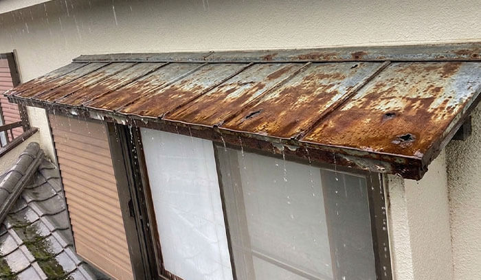 劣化した出窓上部の板金に雨が打ち付ける様子