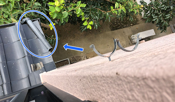 風で落下した雨どいが下屋根に引っかかっている